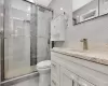 Bathroom featuring toilet, a shower with door, and vanity