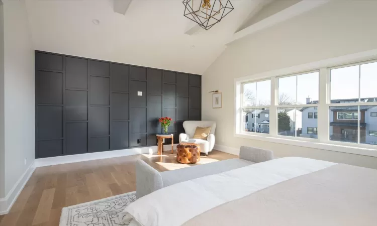 Bedroom with light hardwood / wood-style flooring, lofted ceiling with beams, and a notable chandelier