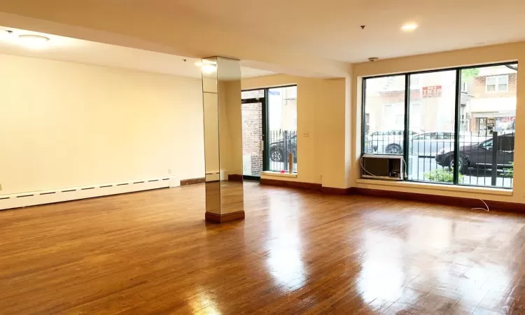 Unfurnished room featuring hardwood / wood-style floors and a baseboard radiator