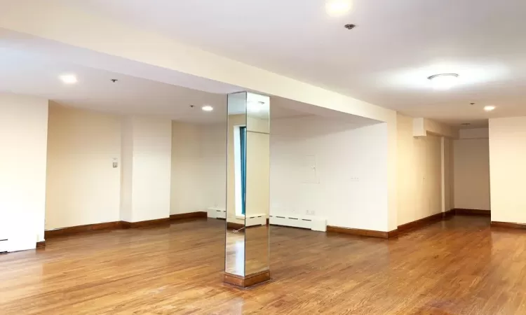 Basement with wood-type flooring and a baseboard radiator