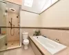 Bathroom with toilet, independent shower and bath, vaulted ceiling with skylight, tile patterned flooring, and tile walls