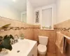 Bathroom featuring tile walls, toilet, and vanity