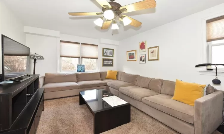 Carpeted living room featuring ceiling fan