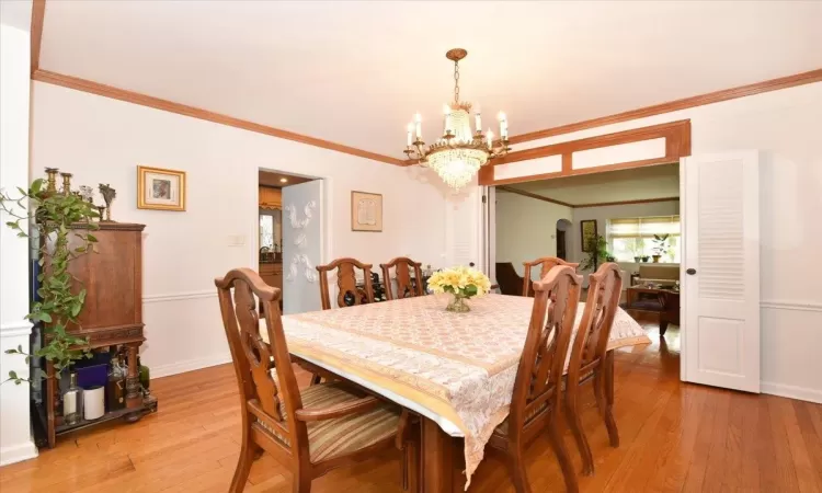 Dining area with light wood-type flooring, crown molding, and a chandelier