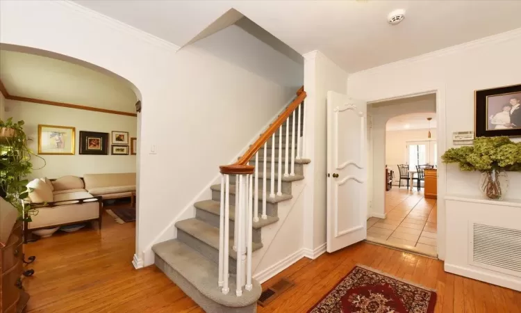 Stairway with crown molding and hardwood / wood-style floors