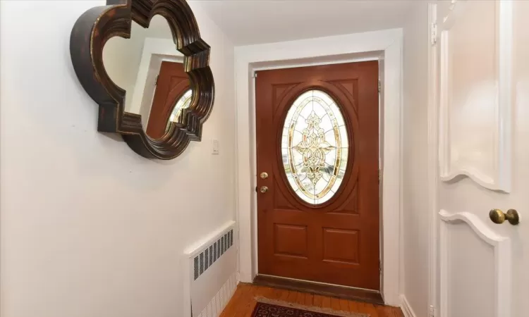 Doorway to outside featuring radiator heating unit and hardwood / wood-style flooring