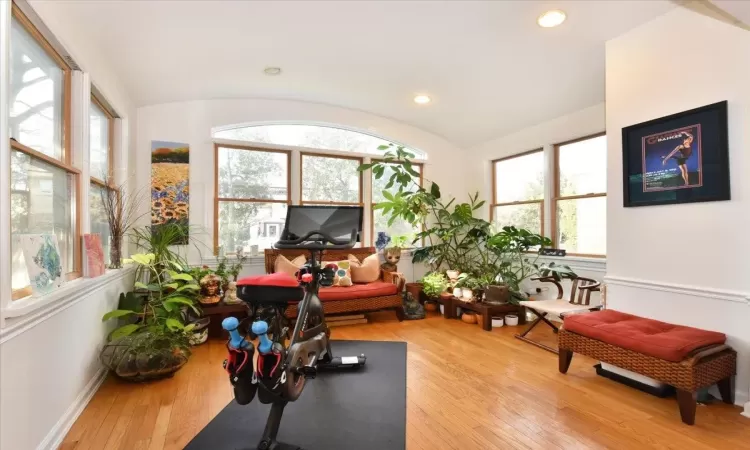 Exercise area with lofted ceiling, wood-type flooring, and plenty of natural light