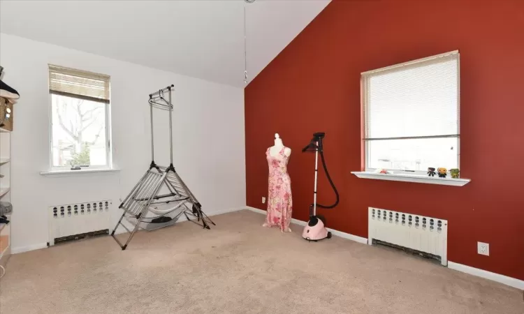 Miscellaneous room featuring vaulted ceiling, radiator heating unit, and carpet flooring