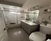 Full bathroom with bath / shower combo with glass door, toilet, vanity, and tile patterned flooring