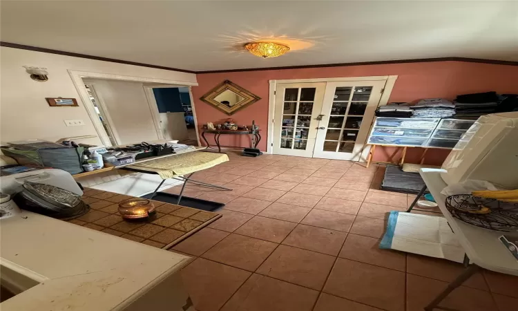 Living room featuring light tile patterned floors, ornamental molding, and french doors