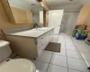 Bathroom with toilet, vanity, tile patterned flooring, and tiled shower