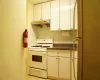 Kitchen featuring white cabinetry, white range with gas cooktop, backsplash, refrigerator, and light tile patterned floors