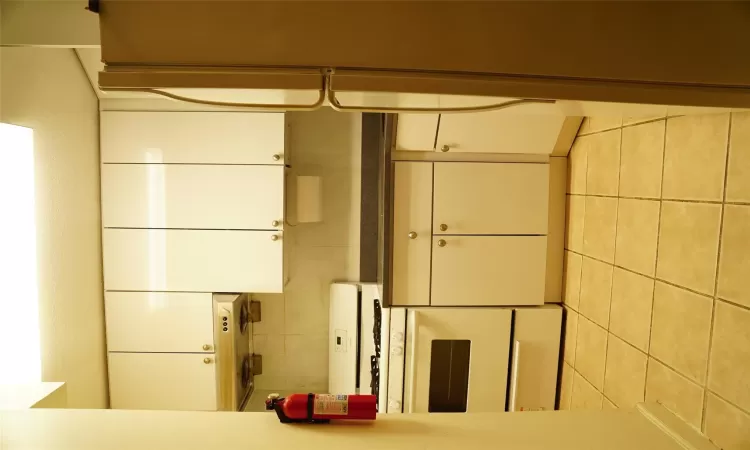 Kitchen featuring ventilation hood, stove, light tile patterned flooring, refrigerator, and white cabinets