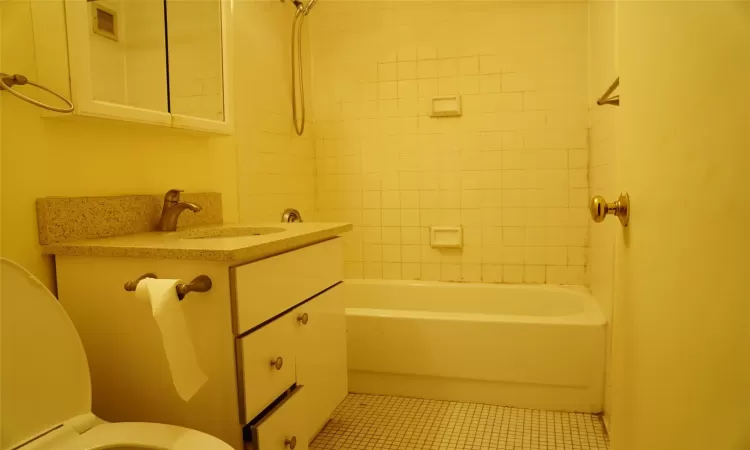 Full bathroom featuring toilet, vanity, tiled shower / bath combo, and tile patterned flooring