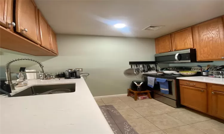 Kitchen with light tile patterned floors, sink, and stainless steel appliances