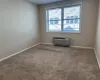 Empty room featuring carpet floors and a wall mounted AC