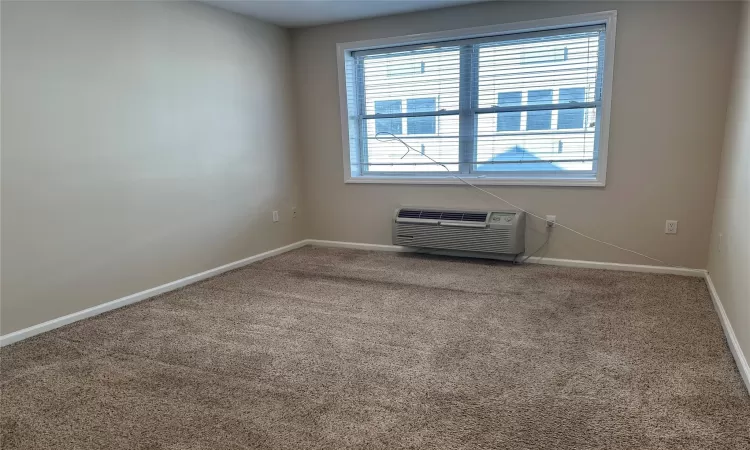 Empty room featuring carpet floors and a wall mounted AC