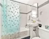 Bathroom featuring tile walls, toilet, and shower / tub combo