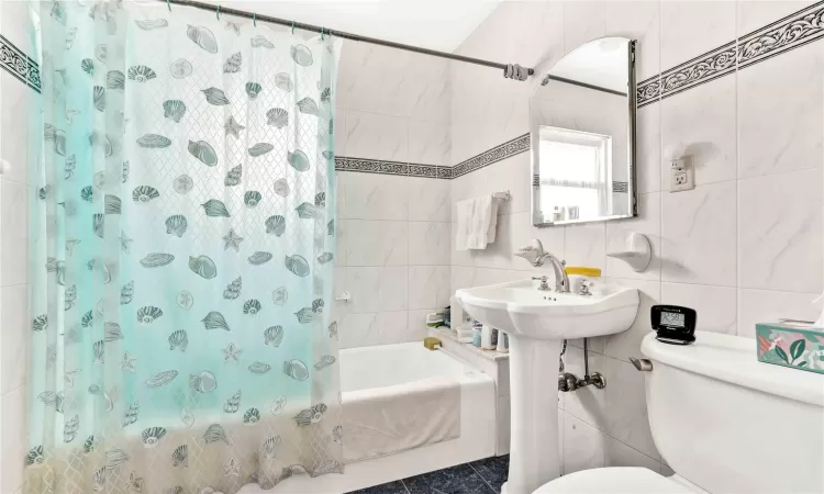 Bathroom featuring tile walls, toilet, and shower / tub combo