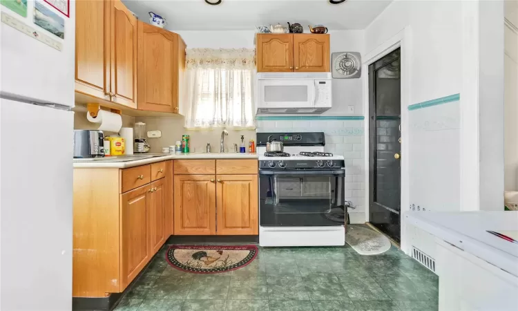 Kitchen featuring backsplash, sink, and white appliances