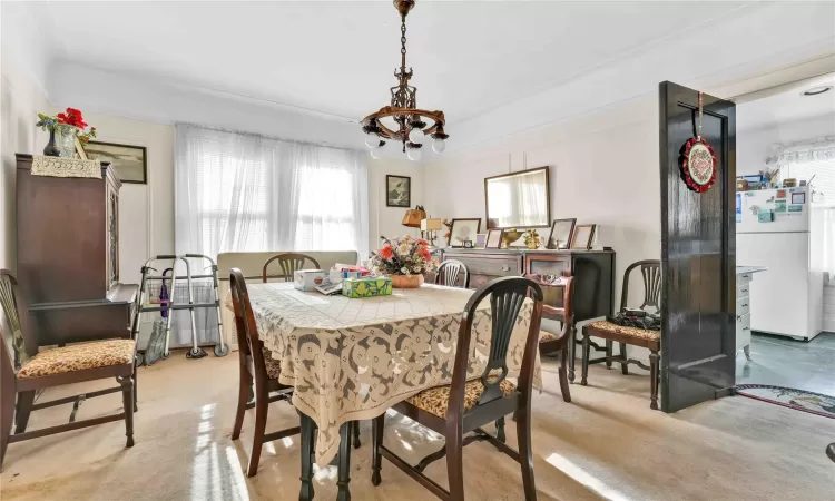 Carpeted dining room featuring an inviting chandelier and a wealth of natural light