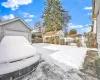 Yard layered in snow featuring a garage and an outdoor structure