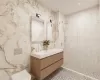 Bathroom featuring toilet, vanity, tile walls, and a tile shower