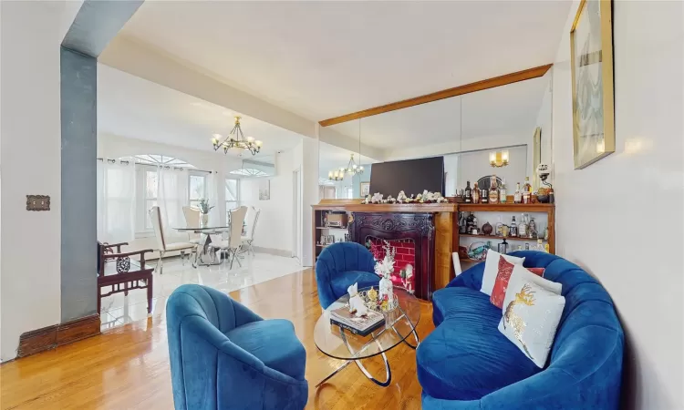 Living room featuring light wood-type flooring, an inviting chandelier, and beamed ceiling