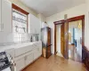 Kitchen with gas range oven, white cabinets, stainless steel fridge, and sink