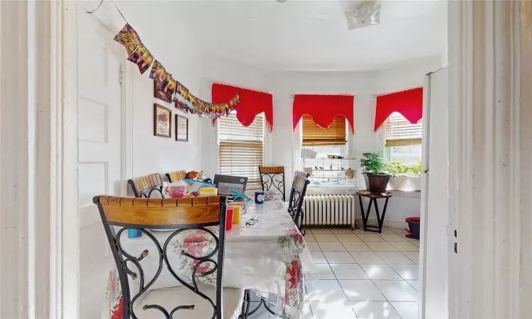 Dining area with tile patterned floors and radiator heating unit