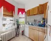 Kitchen with white appliances, radiator heating unit, sink, backsplash, and light tile patterned flooring