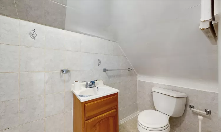 Bathroom featuring vaulted ceiling, toilet, and vanity