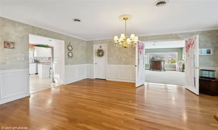 Unfurnished dining area featuring crown molding, light hardwood / wood-style floors, and a notable chandelier