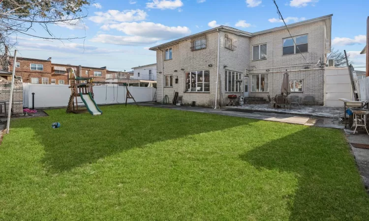 Rear view of property featuring a playground, a patio area, and a yard