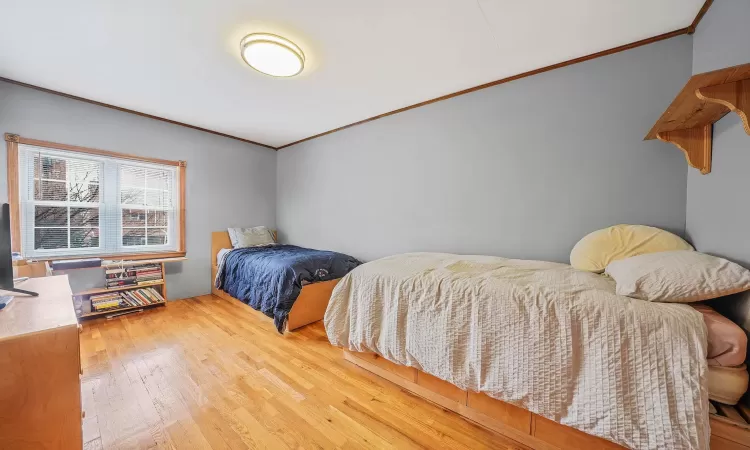 Bedroom with crown molding and wood-type flooring