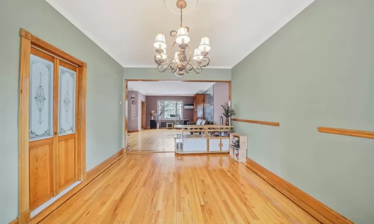 Entryway featuring light wood-type flooring, ornamental molding, and a chandelier