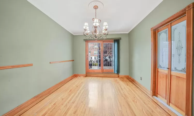 Unfurnished dining area with an inviting chandelier, ornamental molding, and light hardwood / wood-style flooring