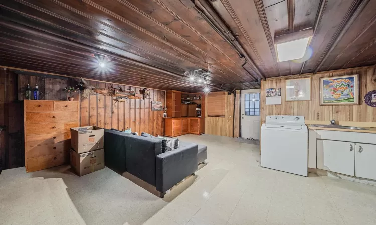 Basement featuring wooden walls, wood ceiling, washer / clothes dryer, and sink