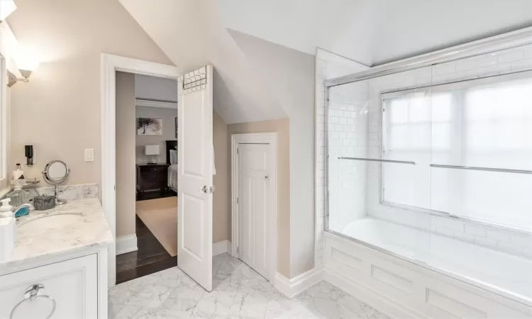 Bathroom with bath / shower combo with glass door and vanity