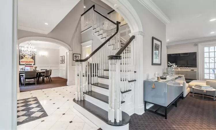 Stairs with a chandelier, ornamental molding, and ornate columns