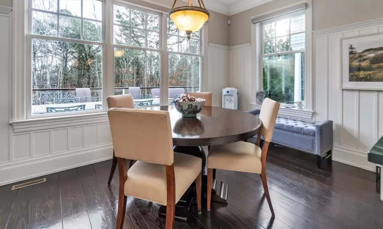 Dining area with a healthy amount of sunlight, dark hardwood / wood-style floors, and crown molding