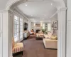 Living room featuring crown molding, dark carpet, and ornate columns