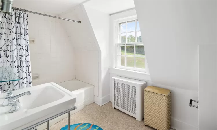 Bathroom with sink, radiator, and shower / bathtub combination with curtain