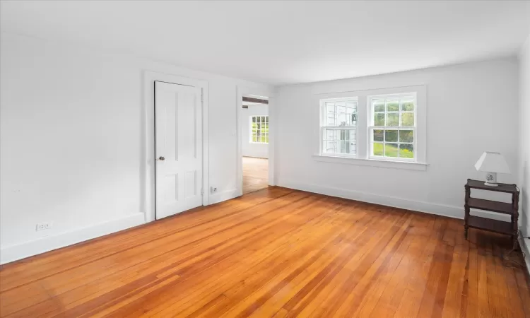 Unfurnished bedroom with a closet, crown molding, hardwood / wood-style flooring, and multiple windows