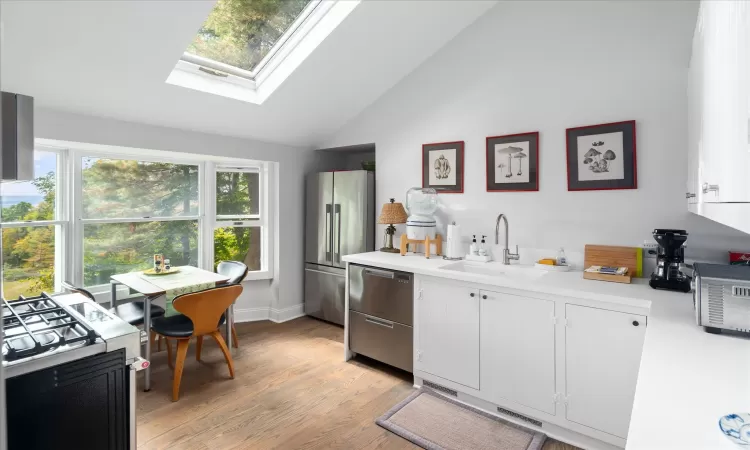 Kitchen featuring light wood-type flooring, appliances with stainless steel finishes, white cabinets, and sink