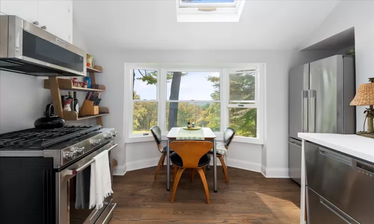 Dining area featuring vaulted ceiling with skylight and dark hardwood / wood-style floors