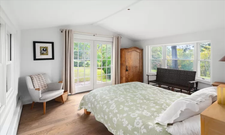 Bedroom with hardwood / wood-style flooring, multiple windows, and vaulted ceiling with beams