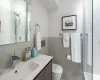 Bathroom with toilet, a shower, tile walls, and vanity