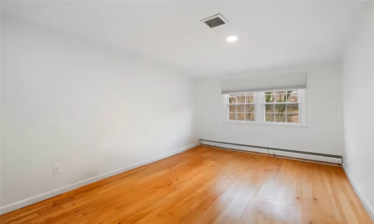 Spare room with baseboard heating and wood-type flooring