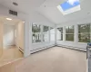 Unfurnished sunroom featuring lofted ceiling with skylight